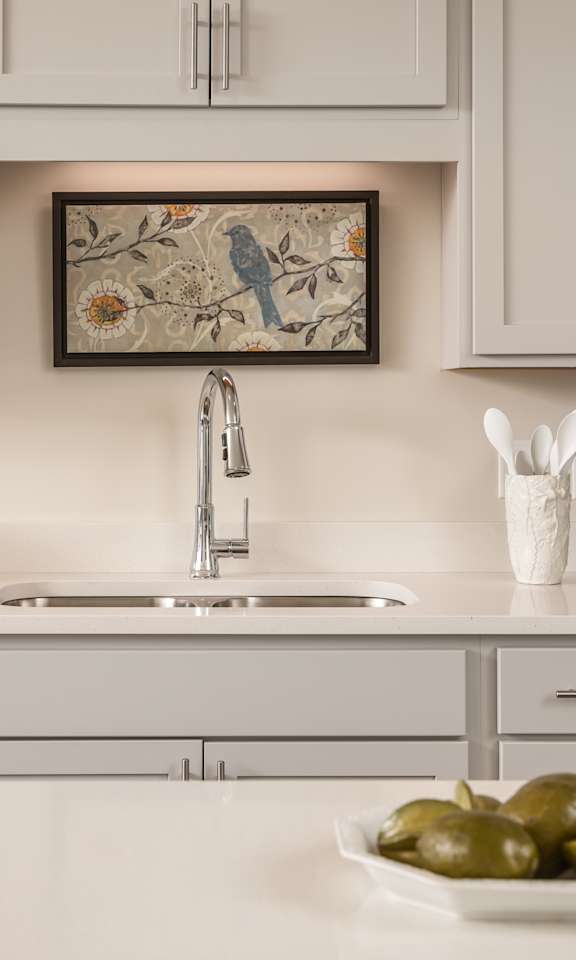 A modern kitchen with a stainless steel oven and a framed picture on the wall.