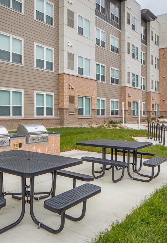 A black table with four benches is in front of a building.