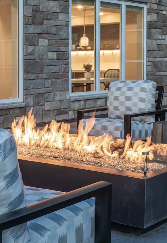 A patio with a fire pit and chairs.