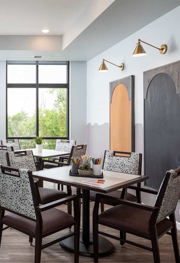a painting studio with tables and chairs and easels and large windows