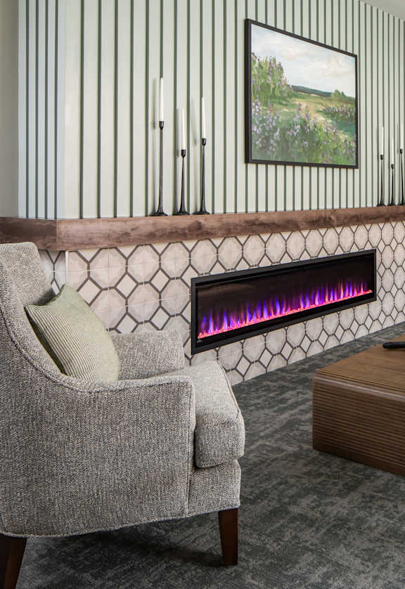 A grey chair is in front of a fireplace in a room.