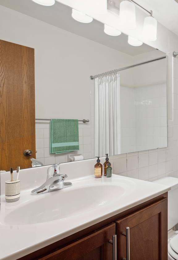 A white bathroom with a toilet, sink, and shower. at Minnehaha Manor, Oakdale, MN, 55128