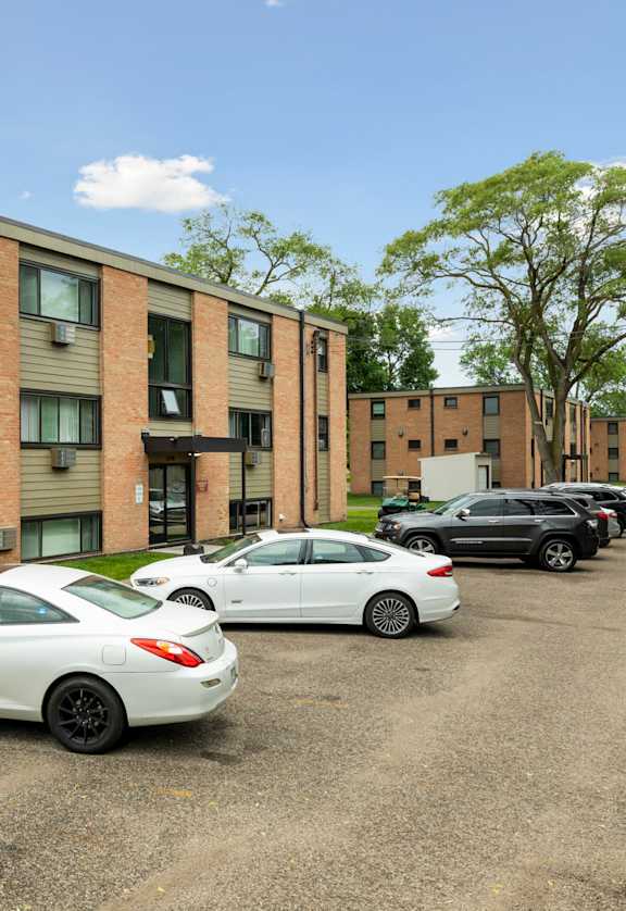 A white car is parked in front of a brick building. at Northeast Villas, Fridley, 55421