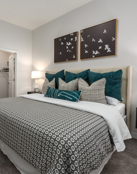 Modern bedroom with large bed, night stand, dresser and door leading to walk-in closet  at Chapter at the Streets of St Charles, Saint Charles, MO, 63303