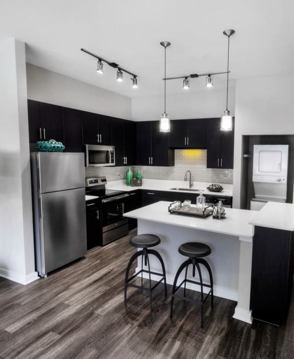 a kitchen with stainless steel appliances and a white island with three stools at Mariposa Lofts, Atlanta, 30307