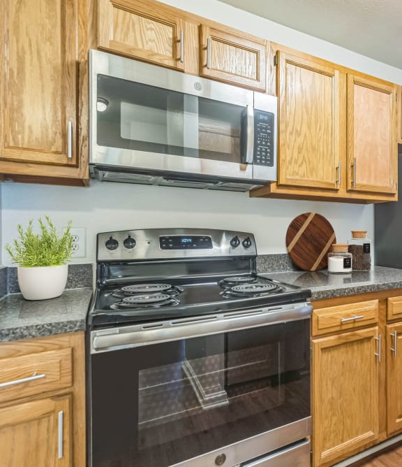 an empty kitchen with wood cabinets and stainless steel appliances  at Sanger Place, Lorton, VA
