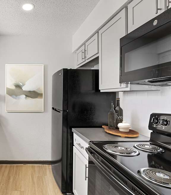 a kitchen with white cabinetry and black appliances at Tradewinds, Windcrest, 78239