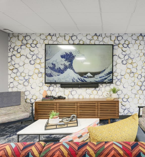 A room with a sofa, chairs, and a television displaying a wave. at Medicine Lake Apartments, Minnesota, 55441