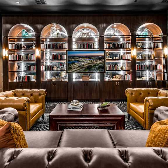 A room with leather sofas and a bookshelf filled with books.