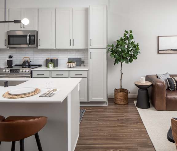 a kitchen with white cabinetry and a white counter top next to a living room with a at Texa Tonka Apartments , Minnesota
