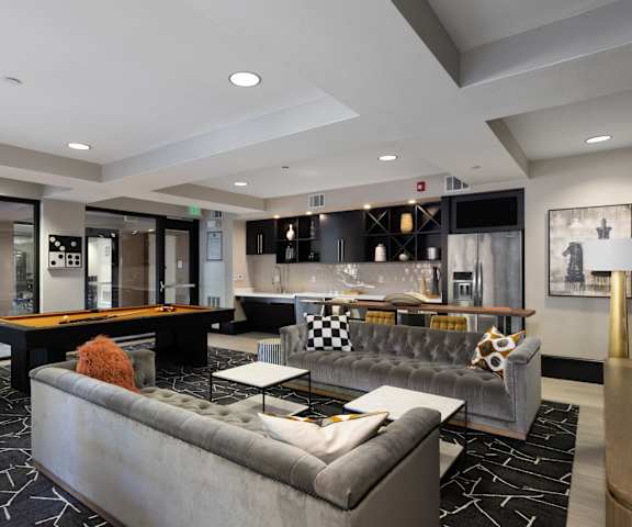 A modern living room with a pool table and a grey sofa.