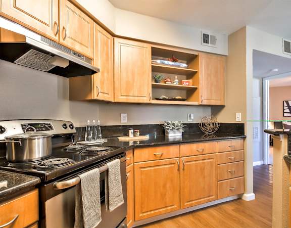 A kitchen with wooden cabinets and black countertops at Rosemeade Apartments, Roseville, 95661