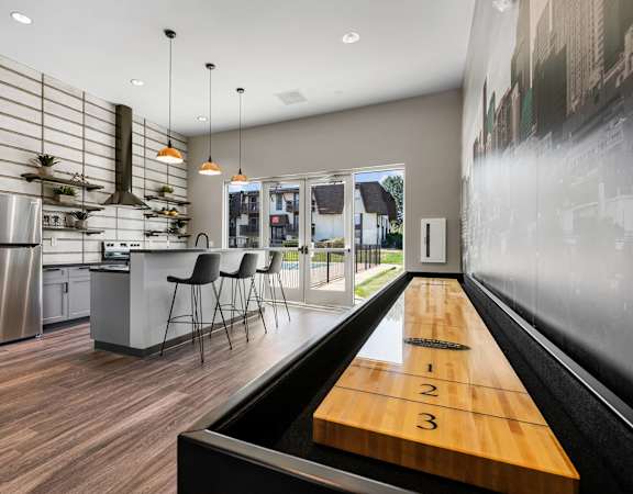 A modern kitchen with a shuffleboard table in the middle.