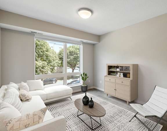 A living room with a white couch, a coffee table, and a chair.