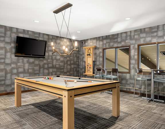 A room with a pool table and a television on the wall.