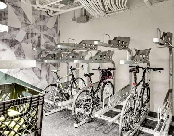 A bike rack with bicycles parked in front of a wall with a geometric pattern.