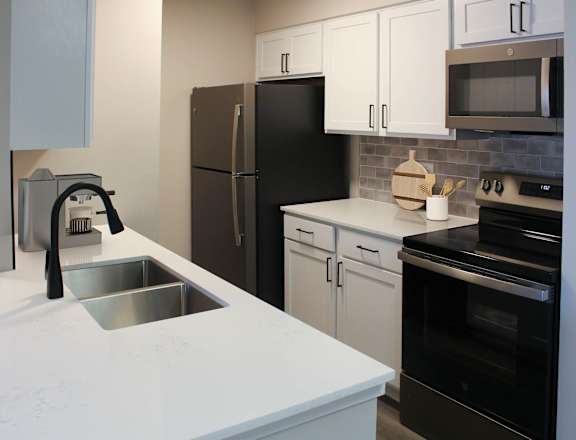 A kitchen with black appliances and white cabinets.