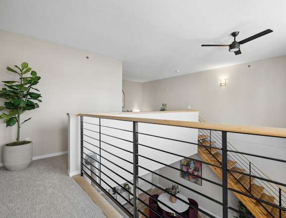A room with a ceiling fan and a staircase.