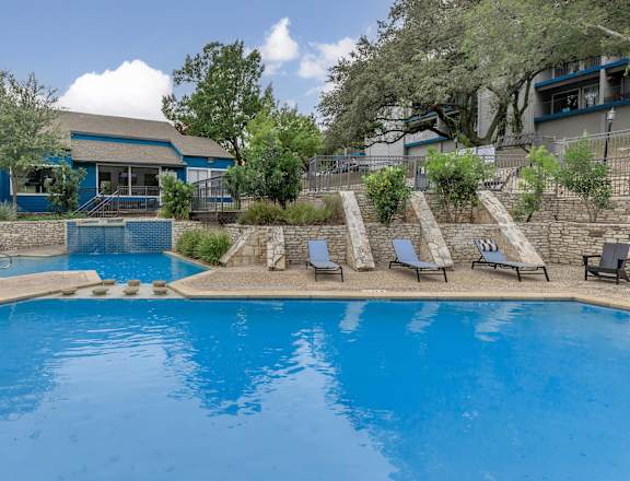 A swimming pool with sun loungers and a building in the background.at The Keller, Texas