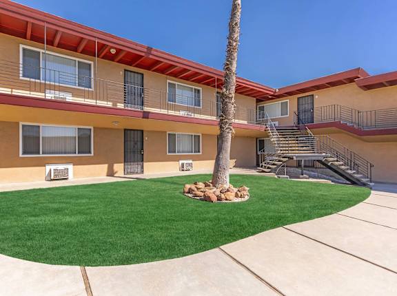 the courtyard of a building with a palm tree and green grass at Oakridge Apartments, Antioch, California