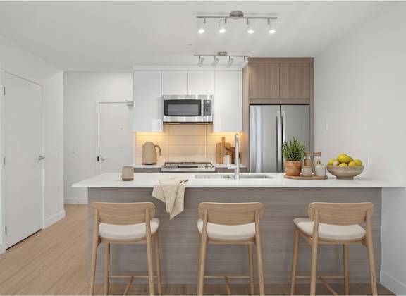 A modern kitchen with a white countertop and wooden bar stools.