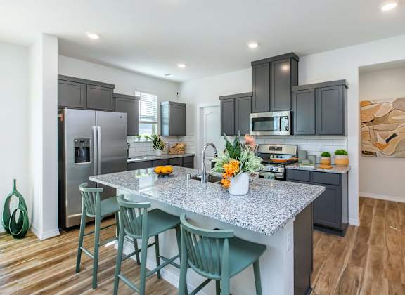 A kitchen with a granite countertop and green chairs.