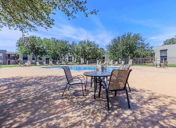 our apartments have a patio with a table and chairs and a pool