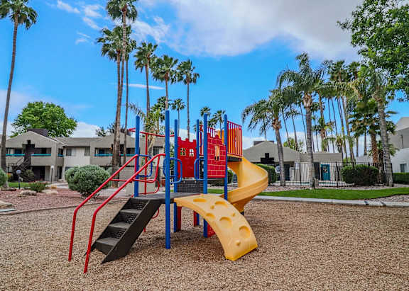 A playground with a yellow slide and red and blue play structures.
