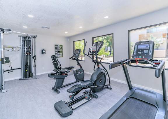 the gym with a treadmill, elliptical, and plank flooring with large windows that overlook the patio at Tides on McDowell, Phoenix, 85035