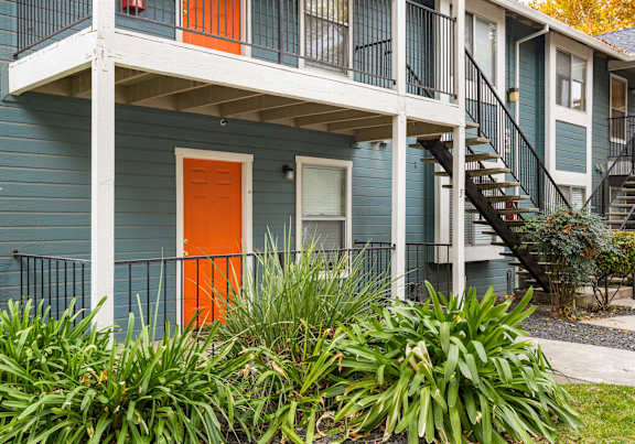 A blue house with an orange door and a white porch.at Redwood Cove Apartments, Chico, 95928
