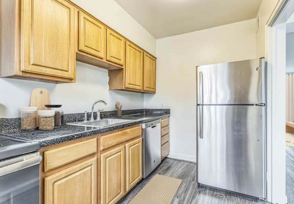 A kitchen with wooden cabinets and a stainless steel refrigerator at The Fields of Silver Spring, Maryland