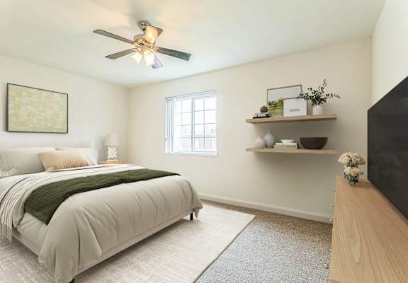 A bedroom with a bed, a ceiling fan, and a window at The Fields of Silver Spring, Maryland