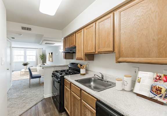 A kitchen with wooden cabinets and a black stove top oven at The Fields of Rockville, Maryland