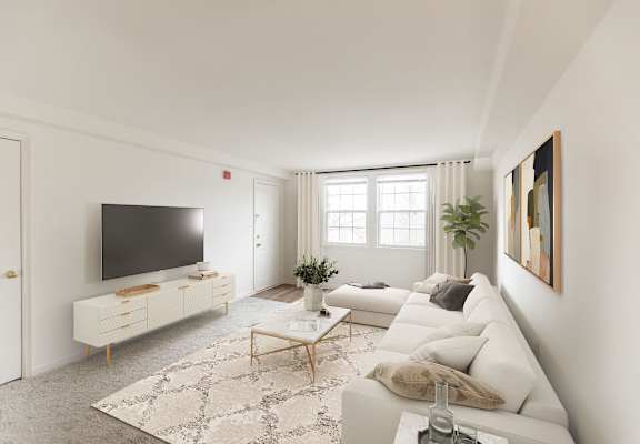 A modern living room with a white couch, a television, and a rug at The Fields of Rockville, Maryland