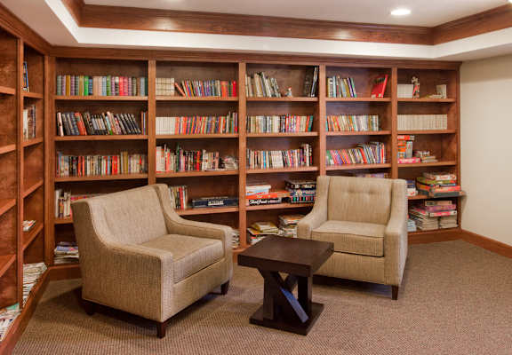 A room with a bookshelf and two chairs.