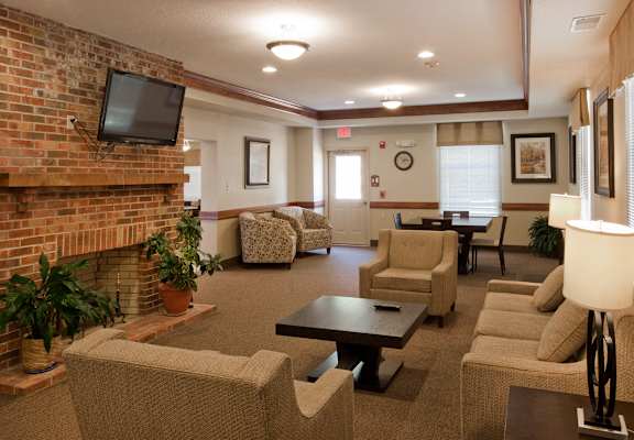 A living room with a brick fireplace and a flat screen TV mounted above it.