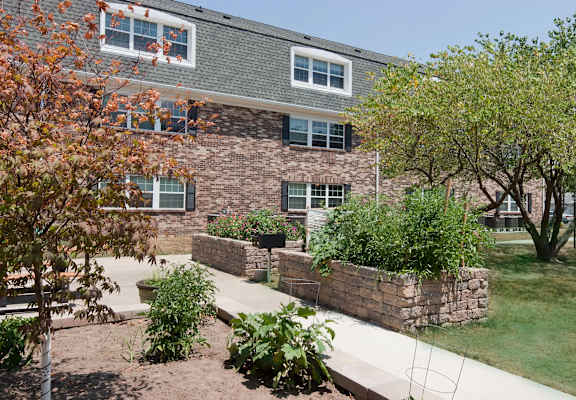 A building with a grey roof and a stone wall in front of it.