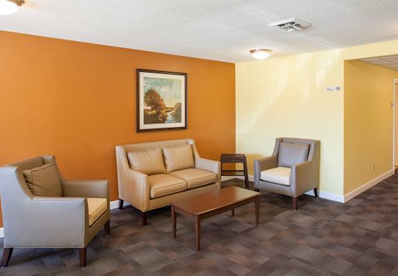 A living room with a brown sofa, two chairs and a coffee table.
