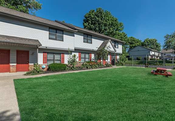 A house with a red garage door and a green lawn.