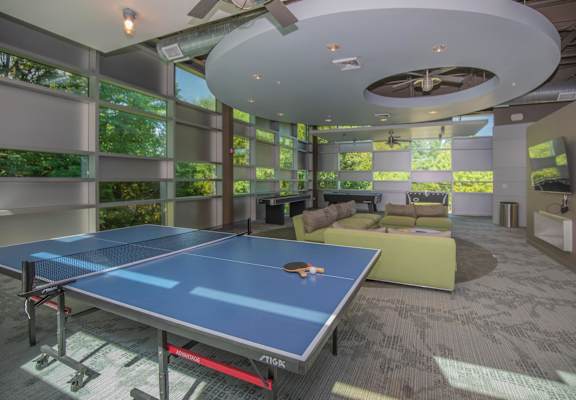 A ping pong table is in the middle of a room with a ceiling fan.