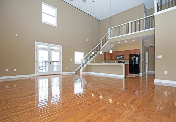 A spacious room with wooden floors and a staircase.
