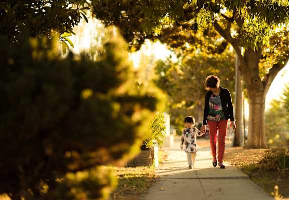 a mother and child walking down a sidewalk