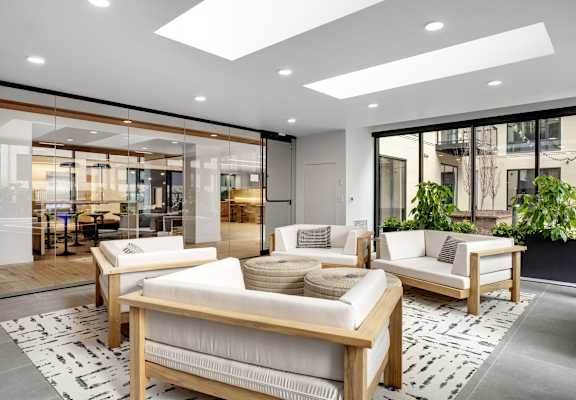 a living room with white couches and chairs and a rug
