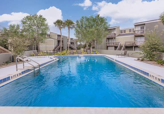 a large swimming pool with apartments in the background
