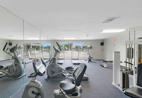 a gym with cardio equipment and mirrors in a building