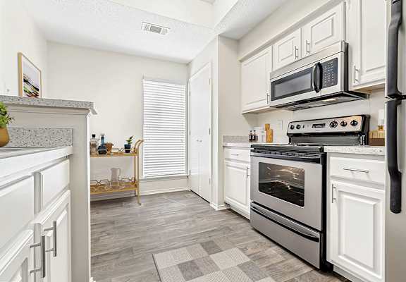 a renovated kitchen with white cabinets and stainless steel appliances