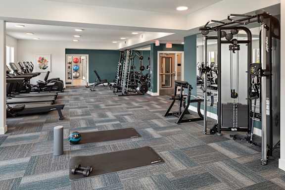 A gym with a variety of equipment including treadmills, weights, and exercise machines.