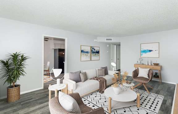 A living room with a white couch, a coffee table, and a plant.