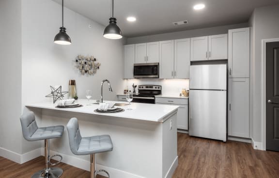 a kitchen with white cabinets and a white island with two chairsat The Station St. Peters, Missouri