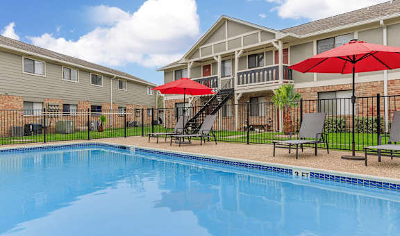 our apartments have a swimming pool with umbrellas at Castlewood Apartments, Clute, TX